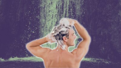 man washing his hair in the waterfall