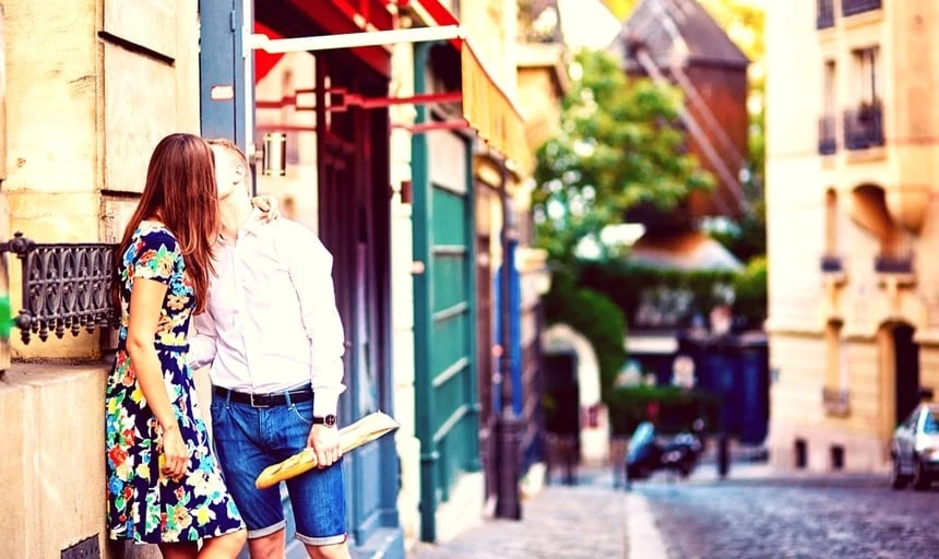 Young romantic couple kissing on Montmartre in Paris holding baguette