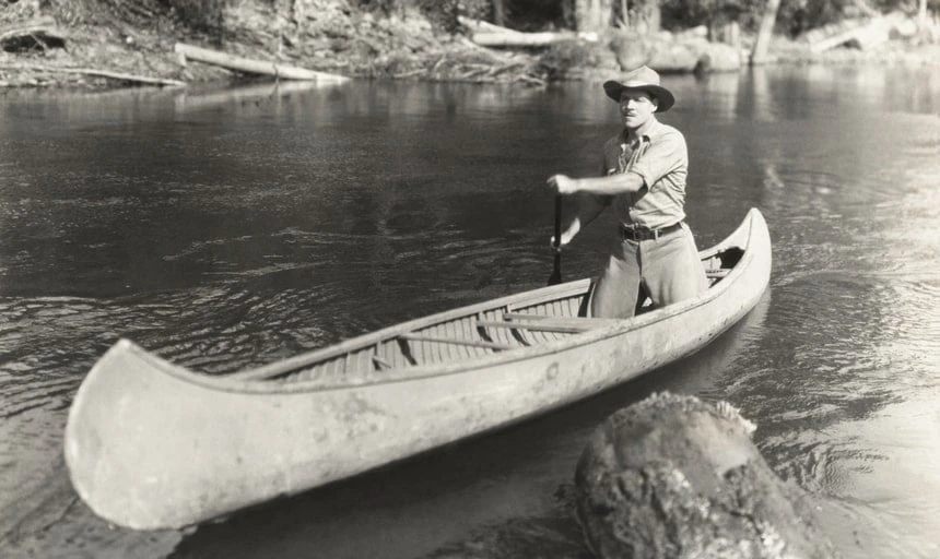 Black and white image of a man conoeing - vintage style