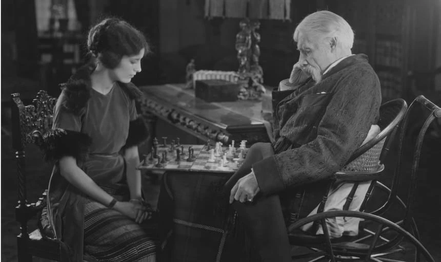 Elderly man and woman deep in thought playing chess - black and white vintage