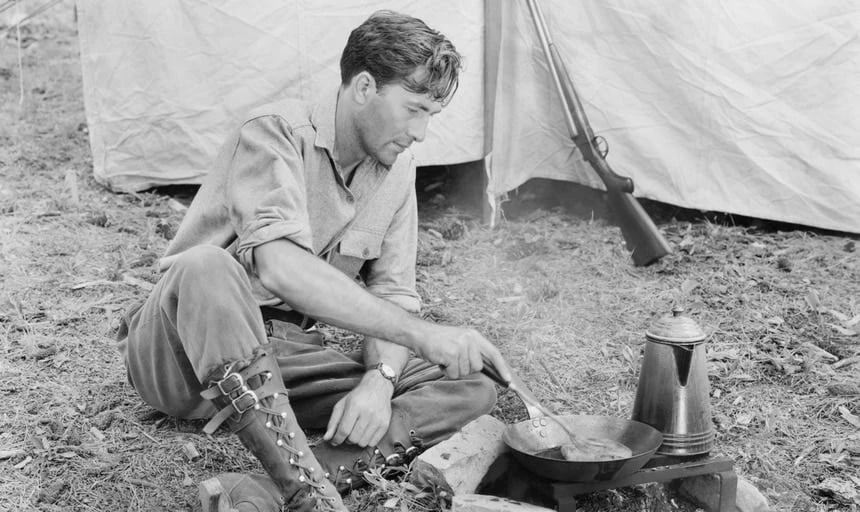 Man cooking outside his tent on a campfire vintage black and white style
