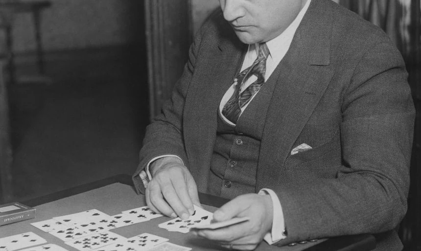 Man in suit playing solitaire - card game, black and white vintage