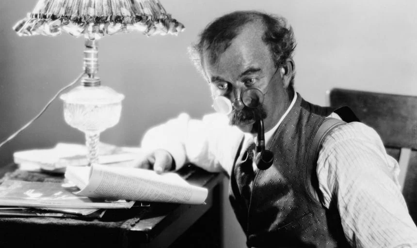 Man with pipe and moustache and glasses reading a book - vintage, black and white style