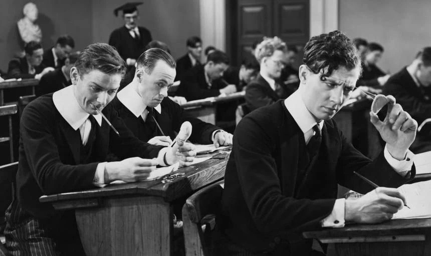 Men in class, one guy smiling, the other guy cheating - black and white, vintage style