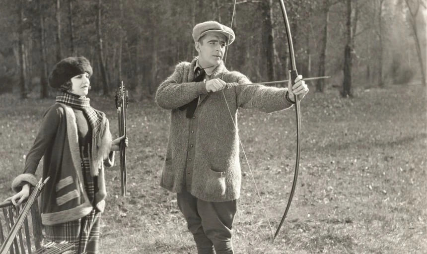Vintage archery image, man drawing bow with woman watching