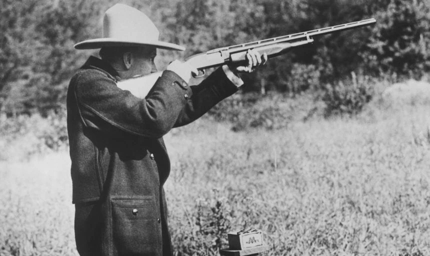 Vintage image of man with rifle wearing hat target shooting