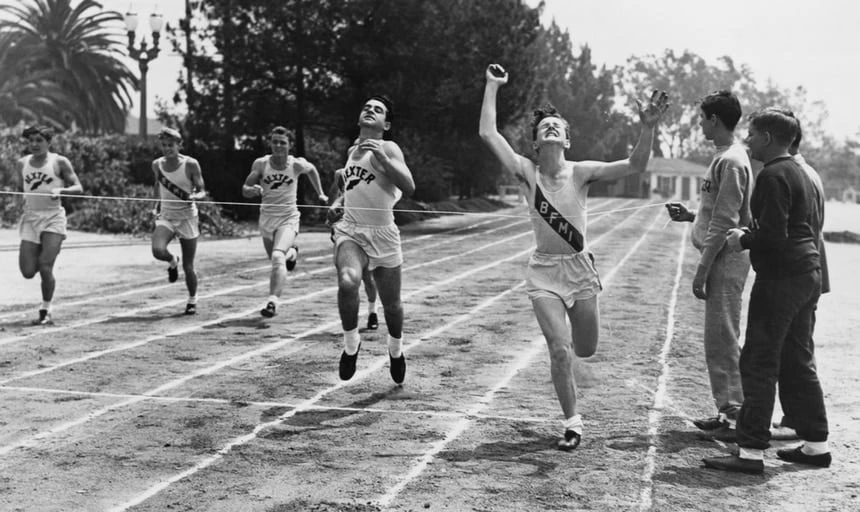 Vintage running race, man straining to get through finish line - black and white