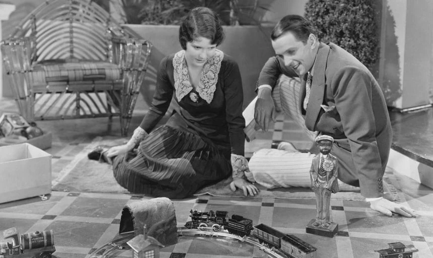Young man and young lady playing with a train set - black and white vintage