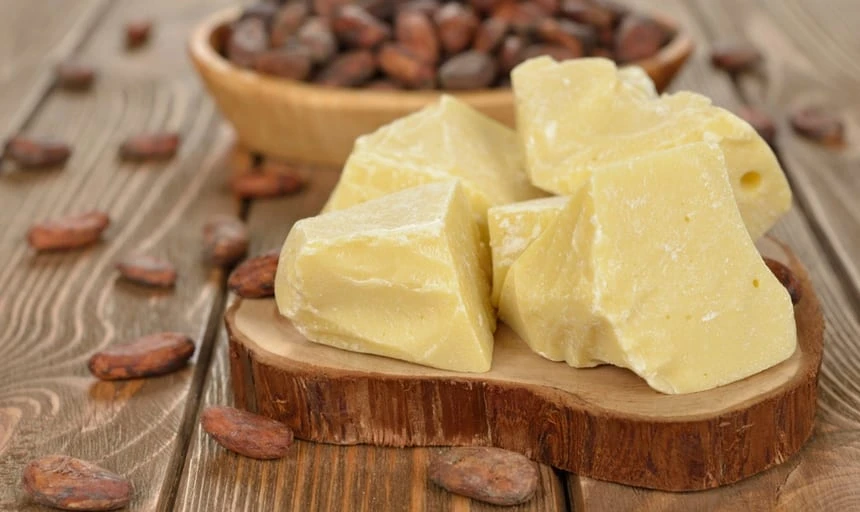 cocoa butter in its natural form on a wooden setting surrounded by cocoa beans