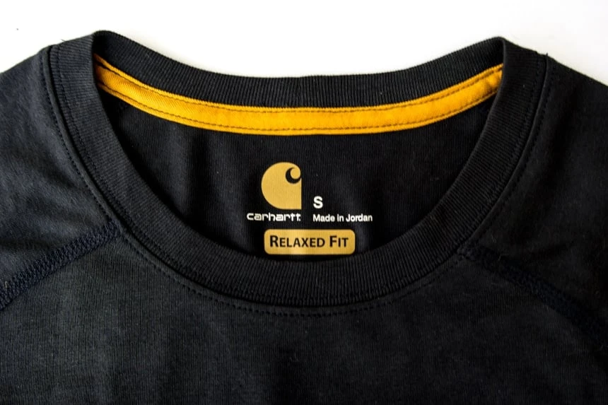 Neck of Carhartt Force Delmont Tee in navy front facing with yellow stitching and size small tag against white background