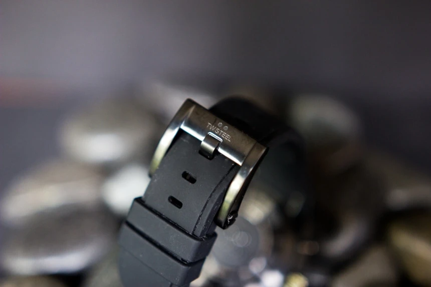 TW Steel CEO Tech watch band and clasp with logo back facing propped on top of black stones on black background a