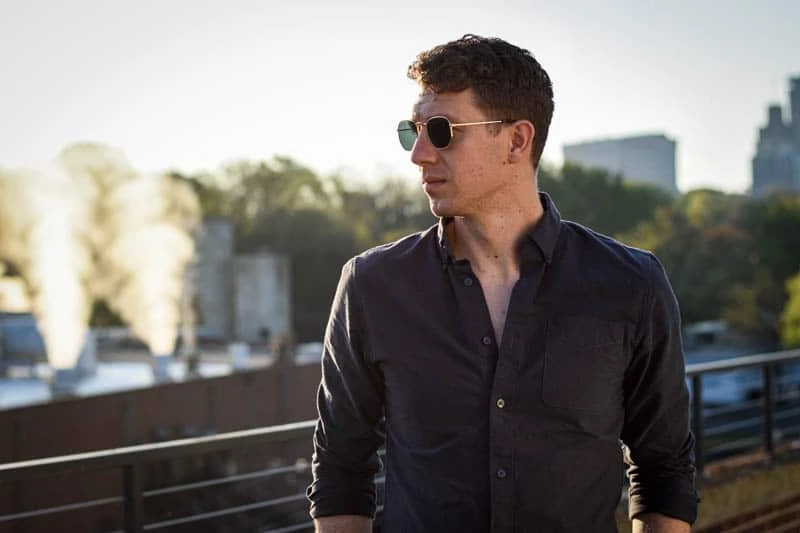 38 Lessons: The Ultimate Guide to Men's Fashion From a Female Perspective 108 blenders eyewear review featured image model wearing whiskey shiner hexagram sunglasses against sunrise