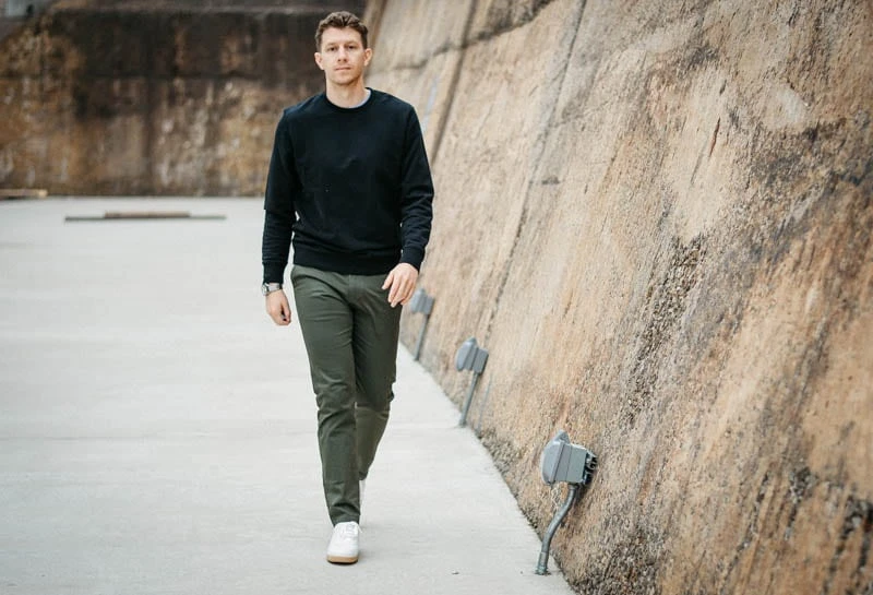 model wearing asket sweater and chinos walking with concrete background