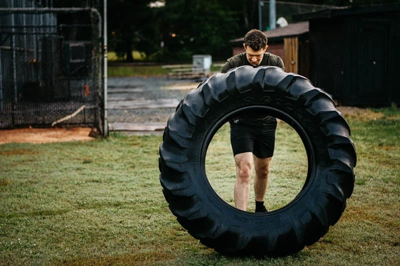 model tipping over tire in vuori kore workout shorts
