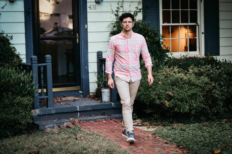 J.Crew Review for Men: Does the Legend Still Have It? 40 model walking out of house with pink madras shirt and performance chinos from J.Crew