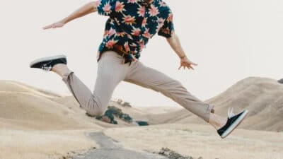 2021/03/Twill-Pants_-Man-Jumping-in-Mid-Air-in-The-Desert-Wearing-Twill-Pantsinos-and-Floral-Shirt-With-Hands-Out.jpgw3.webp