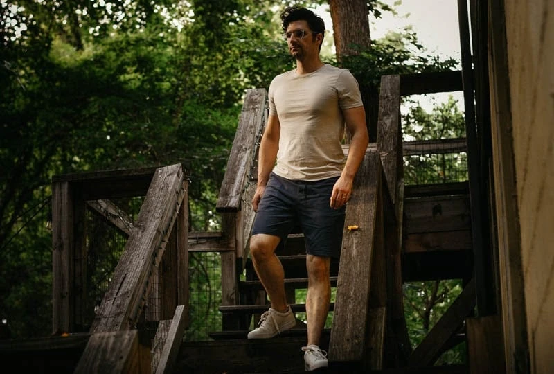 5 Best Workout Shorts for Men: Bring on the Sweat 45 model walking down wooden steps wearing basic man shirt and public rec shorts