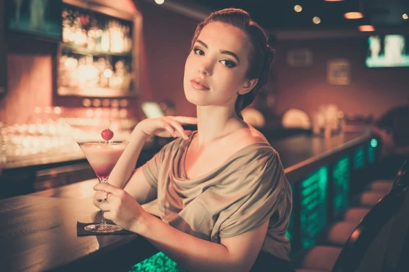 Beautiful Woman Sitting at Bar Drinking Cocktail