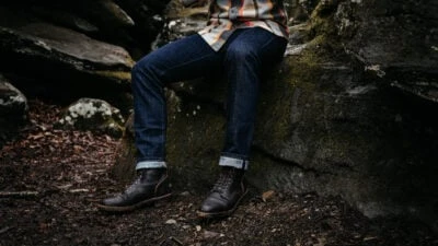 2021/08/How-Should-Jeans-Fit-Model-Wearing-Outerknown-Jeans-and-boots-Sitting-on-a-Rock.jpgw3.webp