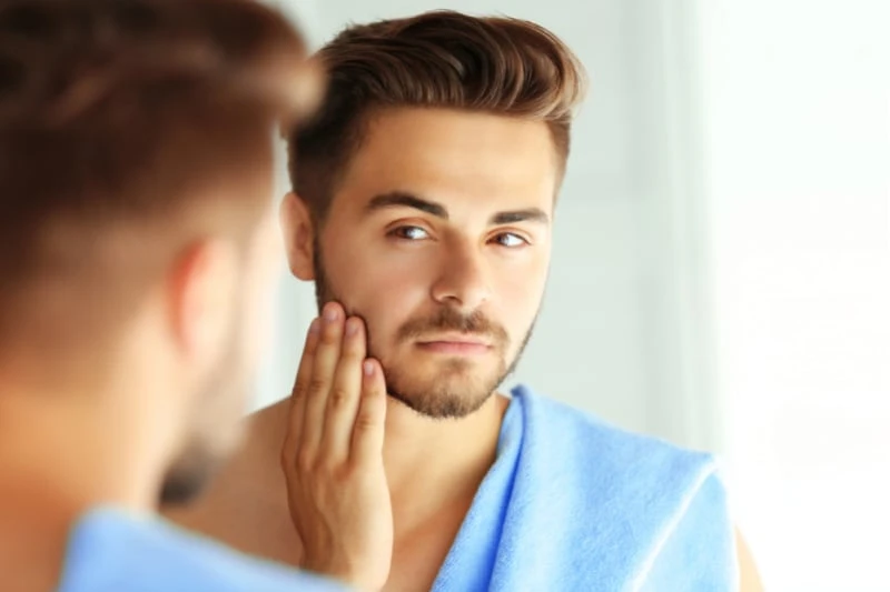 How to Care for Oily Skin: A Man’s Guide for 2024 41 man looking into mirror at facial skin