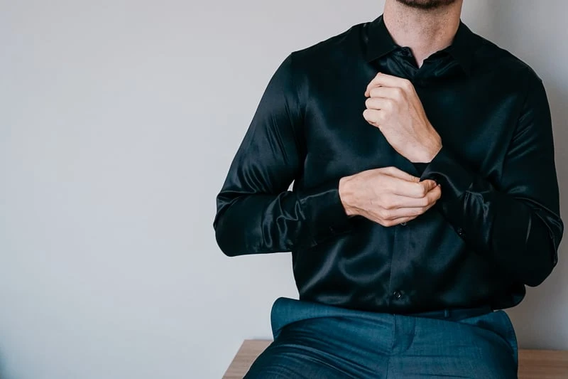 Man wearing silk Lilysilk button up sitting on dresser