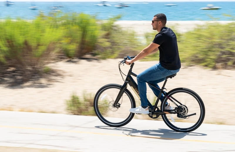 Model riding Aventon ebike near ocean