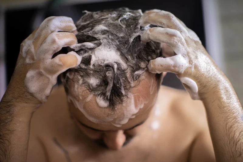 Closeup of man in shower with shampoo in hair
