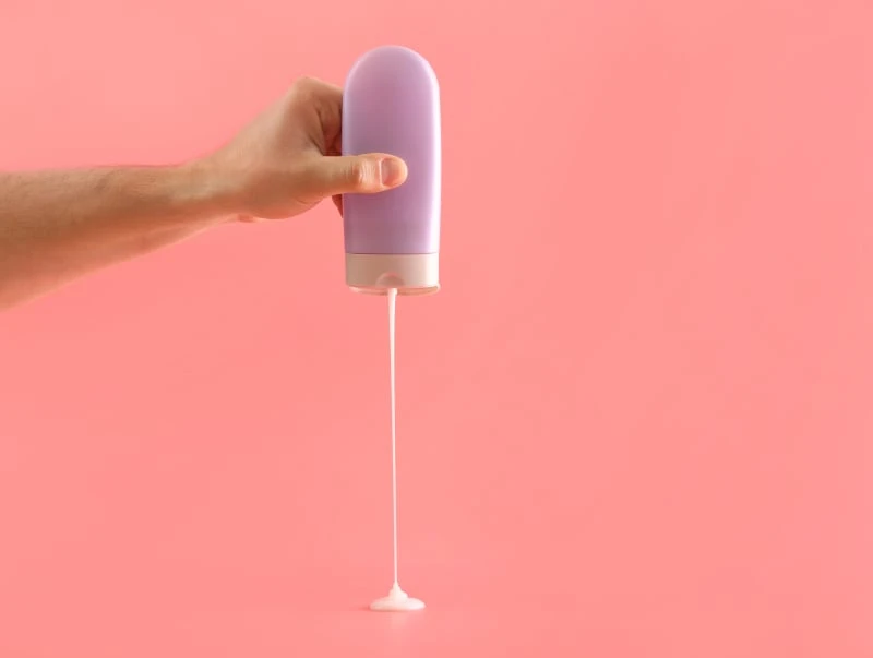 Man squirting shampoo bottle downwards