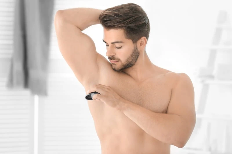 handsome young man using deodorant