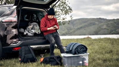2023/06/What-to-bring-camping-as-a-man-Man-outdoors-sitting-car-with-camping-gear-around-him.jpgw3.webp