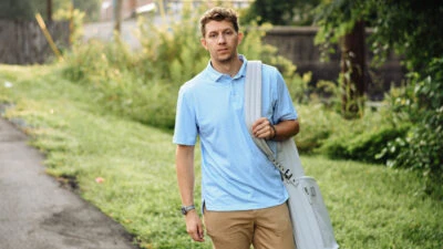 Best Golf Polos for Men Model Wearing Stitch Golf Polo and Holding Golf Bag