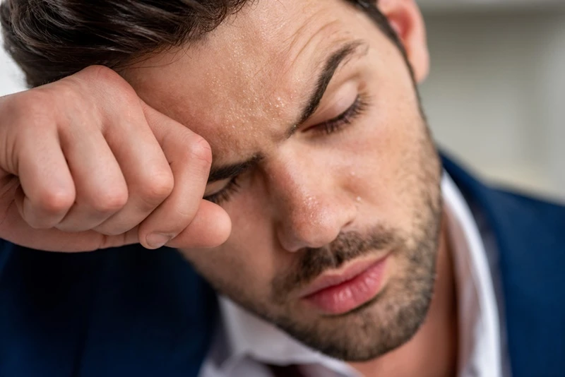 exhausted handsome man holding hand face while suffering heat grey