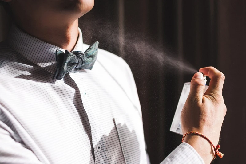 man applying perfume smelling fragrance close