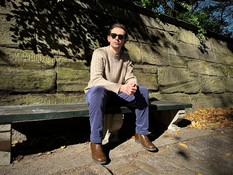 The Adult Man Highland Duds Breckenridge Cable Knit Sitting on Bench