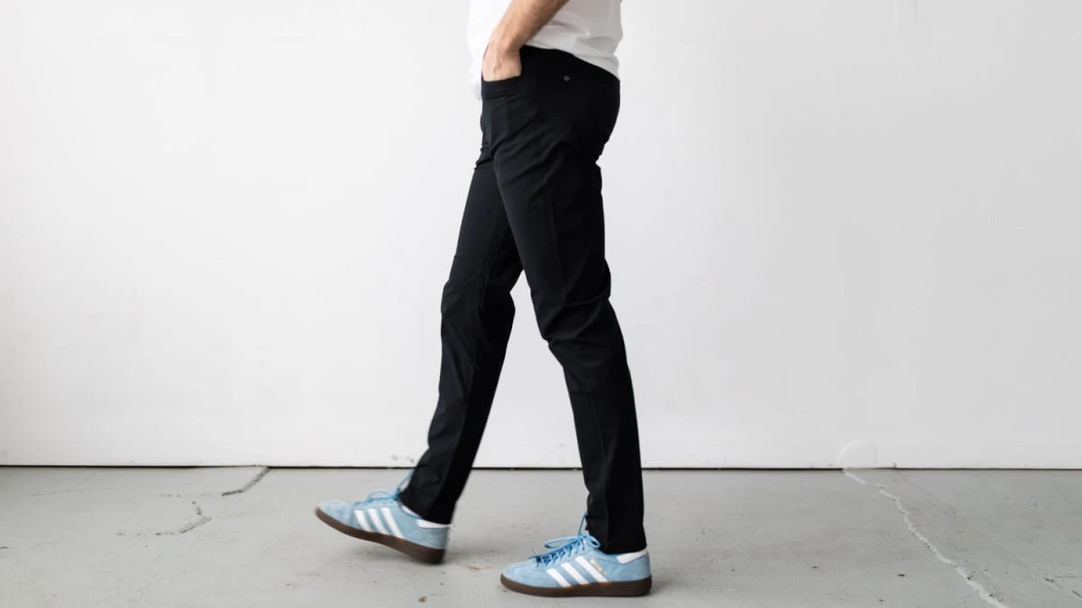 Model Walking Side on in Vuori Meta Pants and Running Shoes