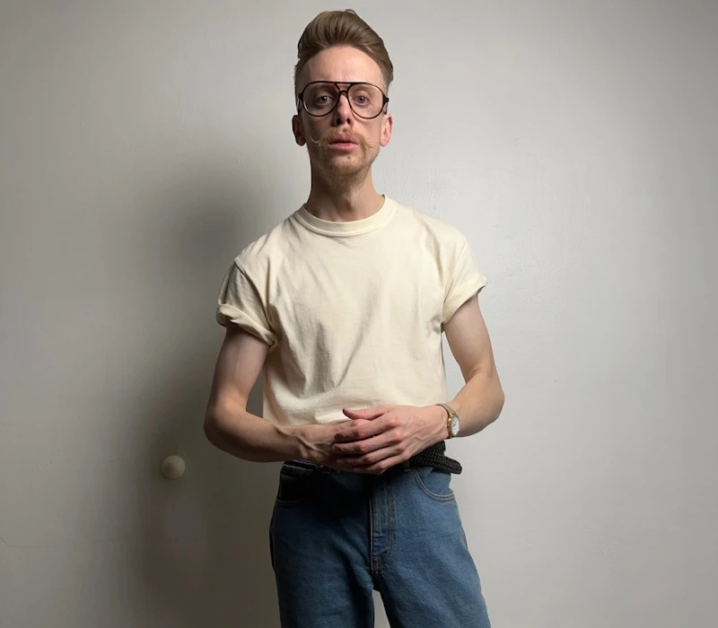 A man wearing a plain shirt with rolled-up sleeves