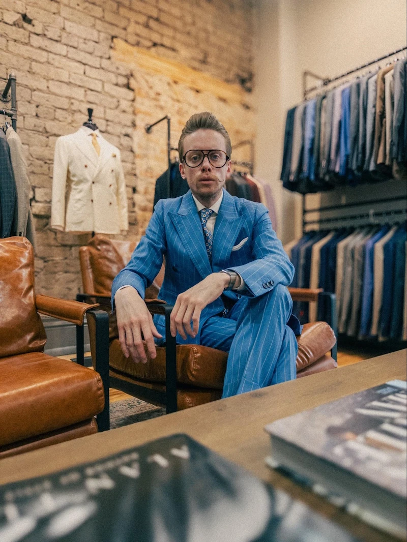 Model Sitting on Chair Wearing Blue Striped Suit