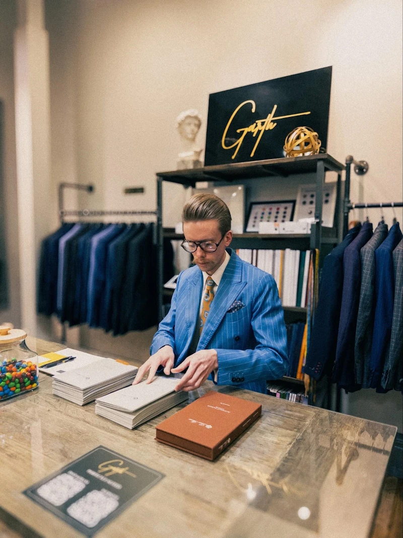 Model Sitting wearing Blue Strpied Suit